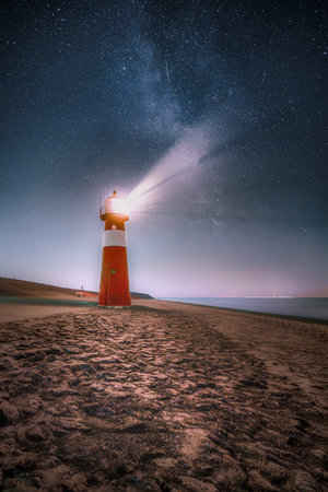 Lighthouse and the Milky Way above the North Sea on the sea dike in Zeeland near Westkapelle, the Netherlandsの写真素材