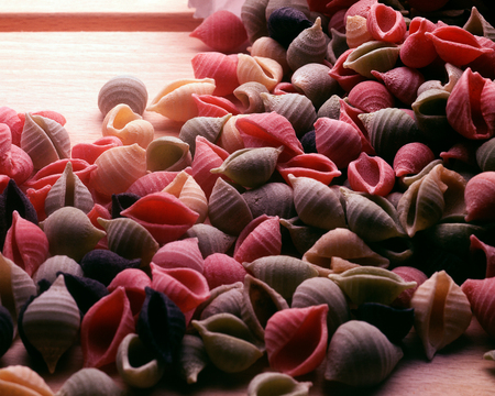 a great variaty of multi-colored pasta on a wooden plate ready to be cookedの写真素材
