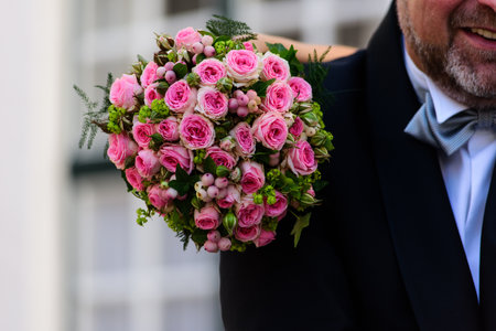 closeup of aa wedding bouquette of roses resting on the shoulder of the groomの写真素材