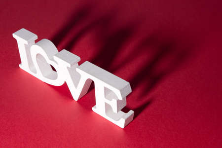 The inscription "Love" with a shadow, on a white and red background. Heart in the inscription. Romantic background.の写真素材