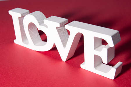 The inscription "Love" with a shadow, on a white and red background. Heart in the inscription. Romantic background.の写真素材