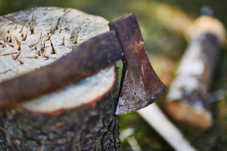Closeup of an rusty axe laying on a chopping block outside