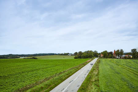 a long road in the country with large green fieldの写真素材