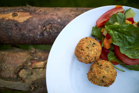 Meatballs and vegetables on a plate outdoors