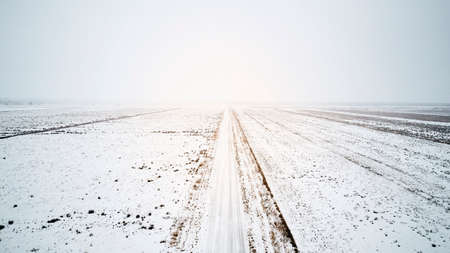 a white snowy road with fog in winterの写真素材