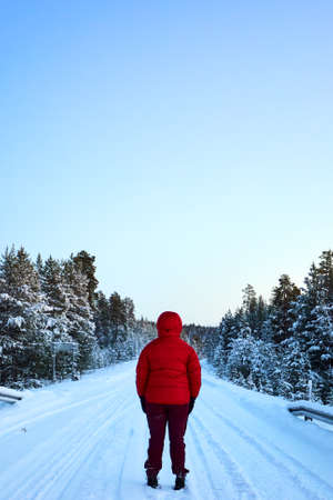 a man in red jacket standing in snowy forestの写真素材