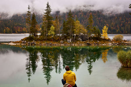 man watching landscape of pine trees in a lakeの写真素材