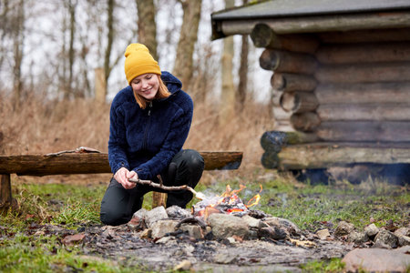 Young woman cooking on a campfire in the woods in autumn.
