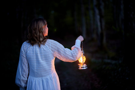 redhead girl in white dress in dark forestの写真素材