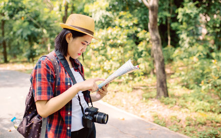 Woman traveler with camera and map in the park. Travel concept.