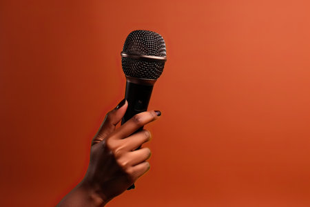 cropped view of african american woman holding microphone on orange backgroundの素材