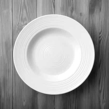Empty white plate on wooden background. Top view with copy space.の素材