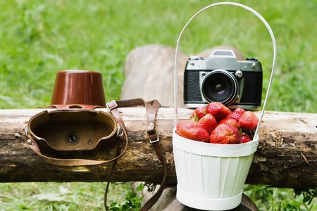 Old camera with a basket of strawberriesの写真素材