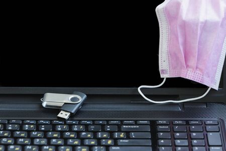 Laptop and notepad with medical mask