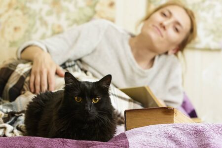Young woman reading a book in bed with her petの写真素材