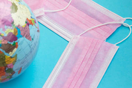 Medical masks and globe on a blue background with space.