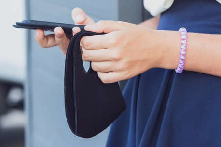 Hands of a girl close-up with a phone and a protective mask
