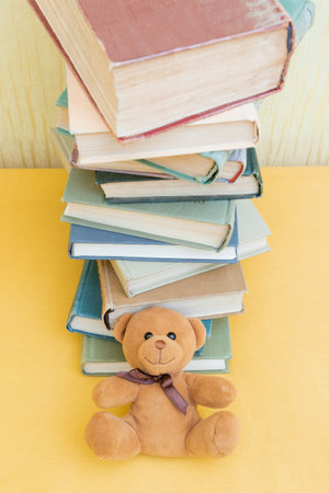 Teddy bear and high stack of booksの写真素材