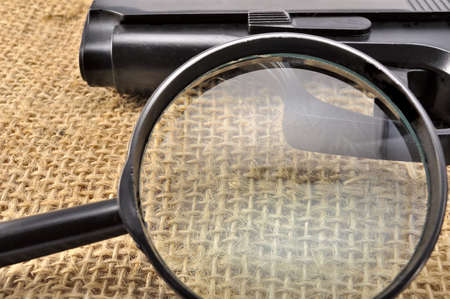 A magnifying glass and a gun in the sack clothの写真素材