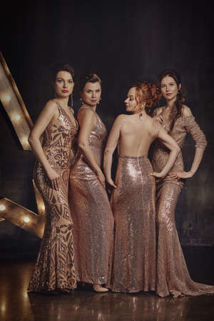 Dazzlingly beautiful girls pose in long evening dresses in the interior.の写真素材