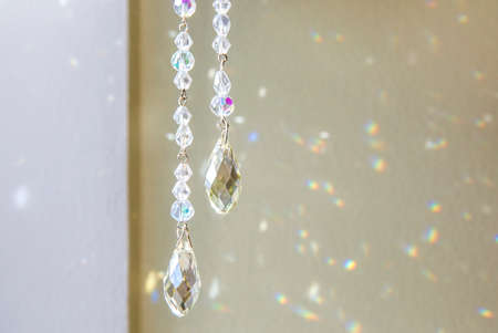 Selective focus on tear drop shape crystal rainbow maker suncatcher hanging in home. Good Feng Shui,...