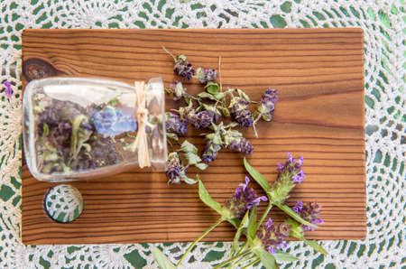 Composition of Prunella vulgaris (known as common self-heal, heal-all, woundwort dry herbal tea powder with fresh fresh flowers on natural wooden board.の写真素材