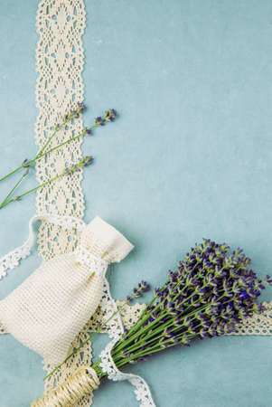 Top view blue patterned background surrounded by bundle of fresh lavender branches and scented dry lavender bag with cotton lace. Romantic vintage background concept.の写真素材