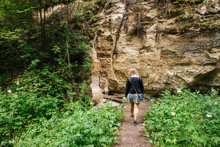 Woman person walking on hiking trail of Hinni canyon, cliff made out of an sand in Estonia.の写真素材