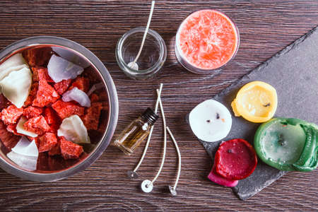 Flat lay of tools for reusing old candles leftovers and making melting a new one: various ingredients on table: candle wicks, glass jar, old candles wax, aroma oil.の写真素材