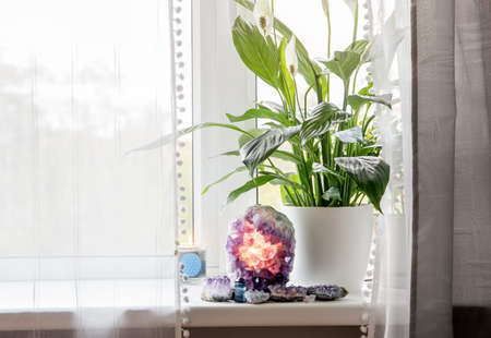Using semi precious stone crystal details in home concept. Amethyst geode lamp burning, spiritual...