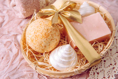 Natural bamboo material gift basket filled with shredded wood excelsior with various spa bathroom products, pink soap bar, bath bomb, natural sponge on vintage light pink background. Beauty present.の写真素材