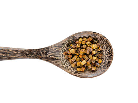 Fermented bee bread also known as fermented bee pollen on wood spoon isolated on white background....