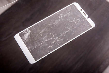 Cracked and broken smartphone screen protection glass.