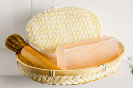 Bar of orange Himalayan crystal Salt Soap on wooden tray with cleaning bath sponge in bathroom.