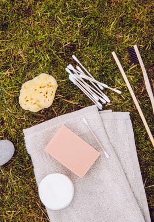 Natural and biodegradable products concept. Various bathroom products on natural green moss outdoors. Flat lay view with lot of copy space. Bamboo fiber towel, cotton swabs, pads, bamboo toothbrush.の写真素材