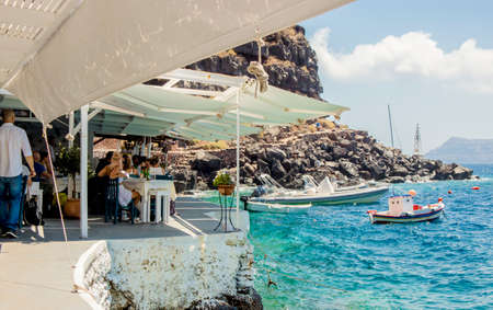 Oia, Santorini/ Greece 14JUL2019-Ammoudy Bay with fishing boats and fish tavernas. Tourists spend time and eat in traditional Greek taverna.のeditorial素材