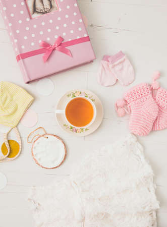 Using herbal breastfeeding tea to increase breast milk production for mothers concept. Different baby things with cup of tea on light white wooden board background, flat lay view studio composition.の写真素材