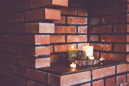 Old broken red brick fireplace, home decor using idea. Covered with wooden discs, pine cones and different candles.の写真素材