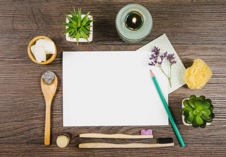 Natural nature friendly beauty products blogger concept. Various skin care treatment products on dark brown wooden table background, top view. Empty white sheet of paper in center.の写真素材