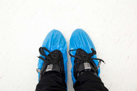 Top view of person`s feet shoes wearing medical antibacterial blue plastic disposable pull on slippers covers in hospital.の写真素材