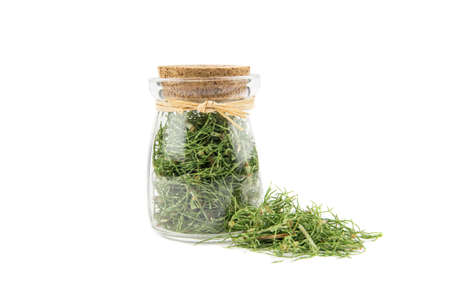 Pile of dried natural herbal medicine called Equisetum arvense the field horsetail or common horsetail isolated on white next to filled glass jar.の写真素材