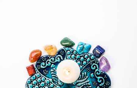Top view of all 7 chakra colors semi precious crystal stones on blue and white ornament background...