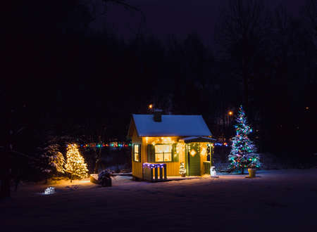 Wooden painted yellow private children`s play house in home garden, decorated with Christmas LED...