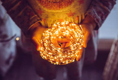 Close up top view of person holding roll of wire micro LED string lights in hands.の写真素材