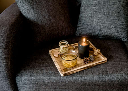 Close up view of minimalist Scandinavian style black color details home decor concept. Wood tray with steaming herbal tea, illuminated black candle, deer antler, pine cones. Top view.の写真素材