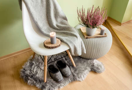 Common pink heather, Calluna vulgaris, ling flower in white pot with gray cozy plaid. Cozy autumn living space concept. Candlelight flame.の写真素材