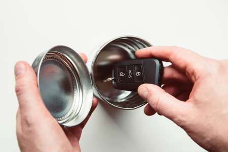 Avoiding high tech start stop system keyless car theft. Man hands put car keys inside metal tin box,...