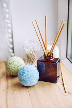Natural wooden bathroom window sill with liquid diffuser bottle with wood sticks, natural light...
