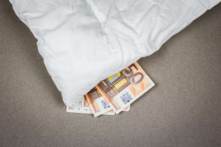 Saving money under the mattress. Saving money concept.の写真素材
