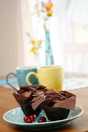 Two chocolate cupcakes covered with chocolate chips on a blue plate. Romantic breakfast for two.の写真素材